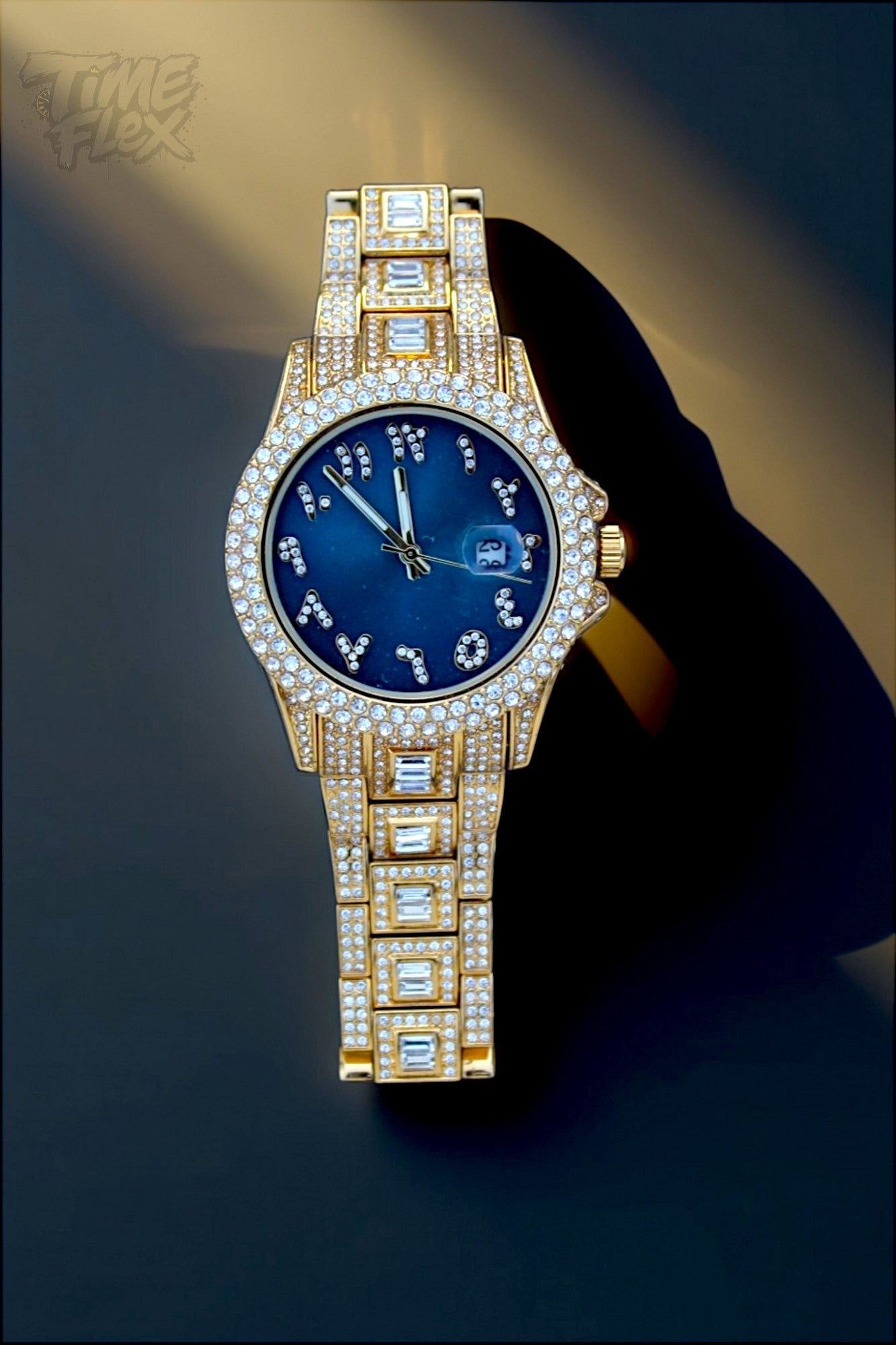 Gold-tone Men's women's watch with diamond-studded bezel, featuring a blue dial with crystal-encrusted Roman numerals and a date display. The watch has a glamorous, sparkling band with rectangular stones, offering a luxurious and stylish look.
