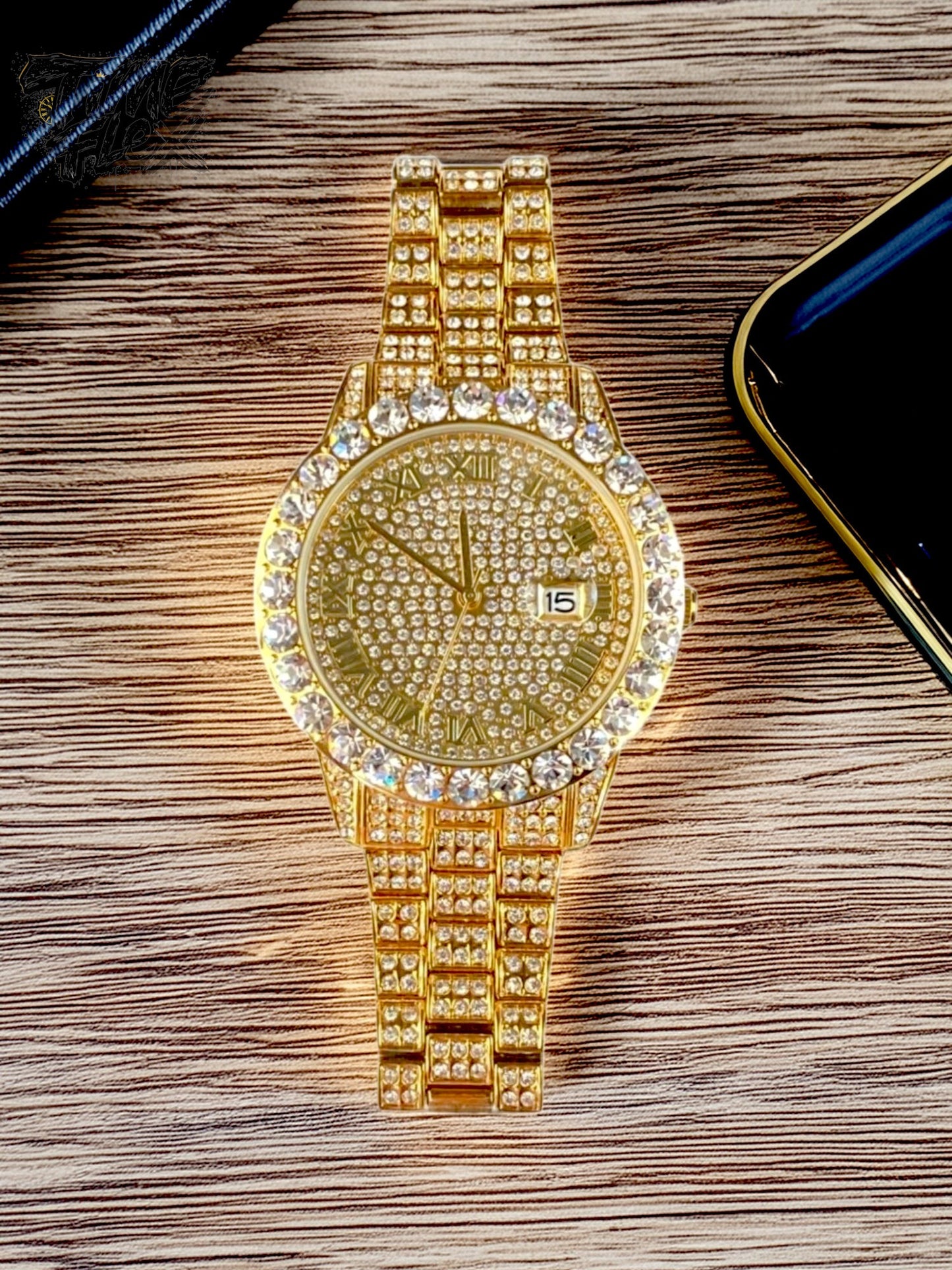 Gold-tone women's and men's watch with a diamond-studded bezel and a sparkling crystal-encrusted band. The watch features a textured gold dial, Roman numeral markers, and a date display at the 3 o'clock position, offering a luxurious and elegant look.