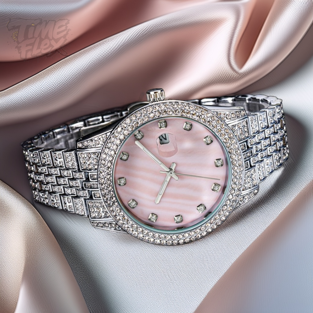 Silver-tone women's watch with a diamond-studded bezel, pink mother-of-pearl dial, and date display at the 3 o'clock position. The watch features a shiny, crystal-encrusted band for a luxurious finish.