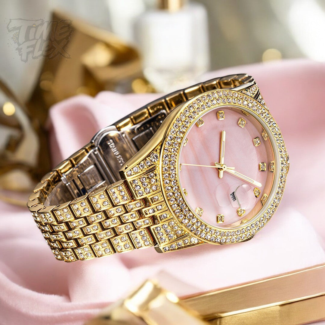 Gold-tone women's watch with a diamond-studded bezel, pink mother-of-pearl dial, and date display at the 3 o'clock position. The watch features a shimmering, crystal-encrusted gold band for a glamorous and luxurious look.