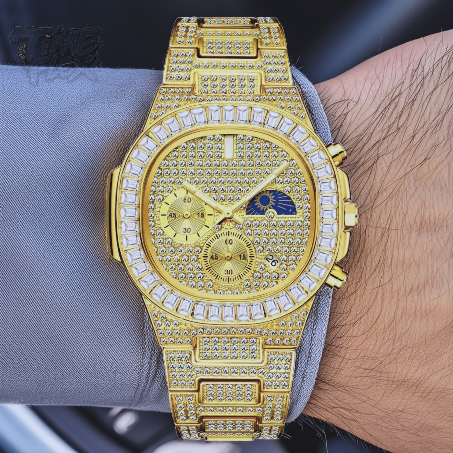 Gold-tone unisex watch with a diamond-studded dial and bezel. The watch features dual sub-dials, a moonphase display, and a sparkling crystal-encrusted band, offering a luxurious and high-end look.