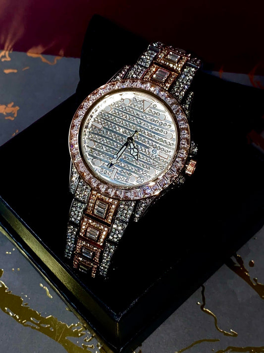 Silver and gold men's women's watch with a diamond-studded bezel and rectangular stone accents on the band. The watch features a sleek white dial with black hands and a date display.