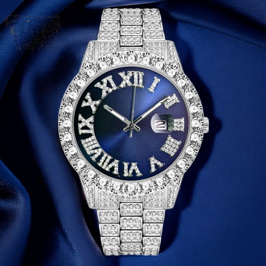 Silver-tone women's watch with a diamond-studded bezel and Roman numeral markers on a blue dial. The watch features a date display at the 3 o'clock position and a sparkling, crystal-encrusted band for a sophisticated, luxurious look.