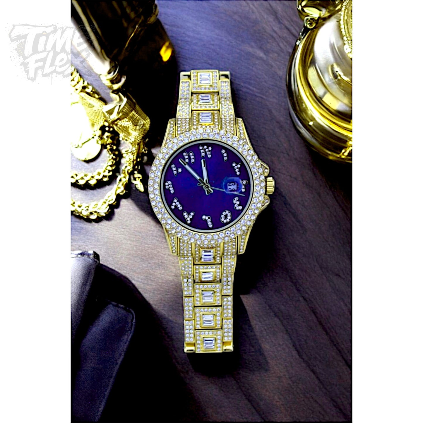 Gold-tone Men's women's watch with diamond-studded bezel, featuring a blue dial with crystal-encrusted Roman numerals and a date display. The watch has a glamorous, sparkling band with rectangular stones, offering a luxurious and stylish look.