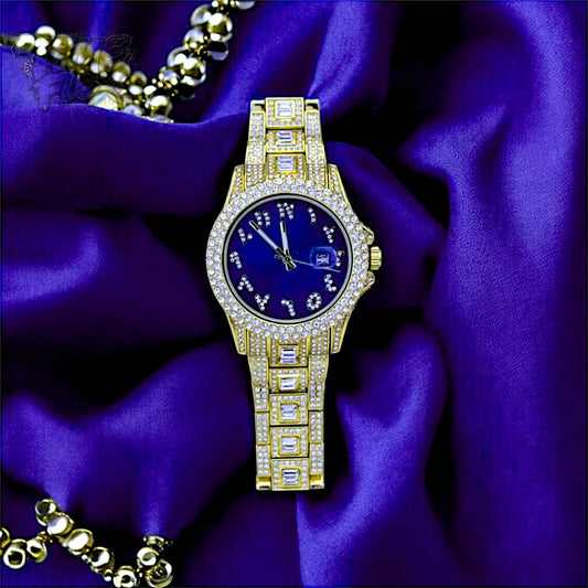 Gold-tone Men's women's watch with diamond-studded bezel, featuring a blue dial with crystal-encrusted Roman numerals and a date display. The watch has a glamorous, sparkling band with rectangular stones, offering a luxurious and stylish look.