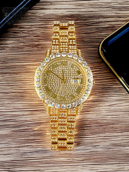 Gold-tone women's and men's watch with a diamond-studded bezel and a sparkling crystal-encrusted band. The watch features a textured gold dial, Roman numeral markers, and a date display at the 3 o'clock position, offering a luxurious and elegant look.