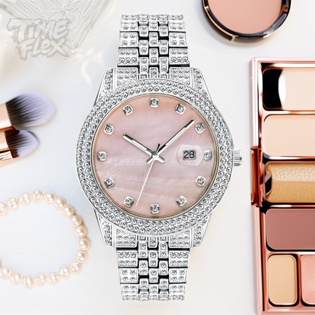 Silver-tone women's watch with a diamond-studded bezel, pink mother-of-pearl dial, and date display at the 3 o'clock position. The watch features a shiny, crystal-encrusted band for a luxurious finish.