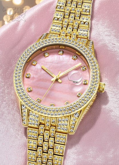 Gold-tone women's watch with a diamond-studded bezel, pink mother-of-pearl dial, and date display at the 3 o'clock position. The watch features a shimmering, crystal-encrusted gold band for a glamorous and luxurious look.