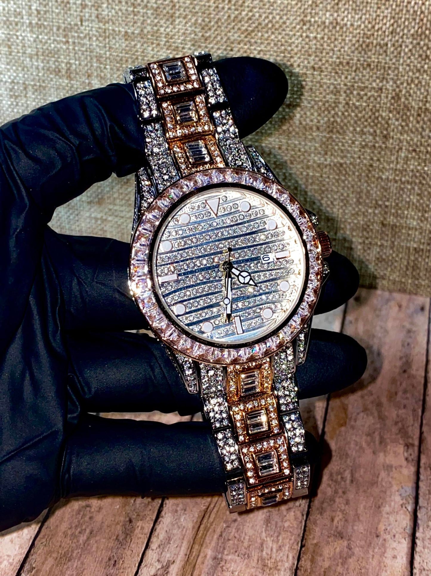 Silver and gold men's women's watch with a diamond-studded bezel and rectangular stone accents on the band. The watch features a sleek white dial with black hands and a date display.