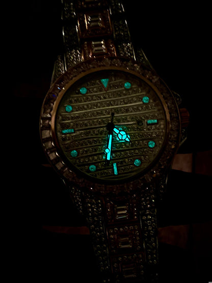 Silver and gold men's women's watch with a diamond-studded bezel and rectangular stone accents on the band. The watch features a sleek white dial with black hands and a date display.